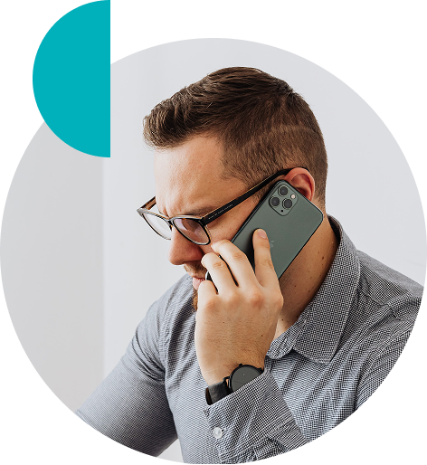 Man with glasses and a checkered shirt holding a smartphone to his ear, appearing to be on a phone call.