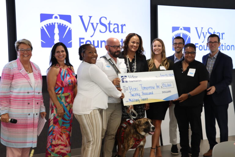 group photo of 9 people holding a large Vystar check for 20,000